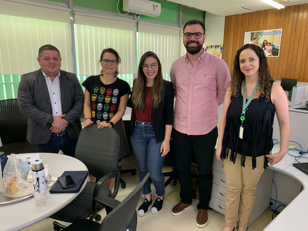 Descrição da imagem: Cinco pessoas posam para a foto. Respectivamente: professor doutor João Paulo Queiroz, representante do Ministério da Saúde, Aliadne Sousa, pesquisadora do NAVI Jordana Paiva, pesquisador do NAVI Pablo Holanda e representante do Ministério da Saúde Kattia Mota. 